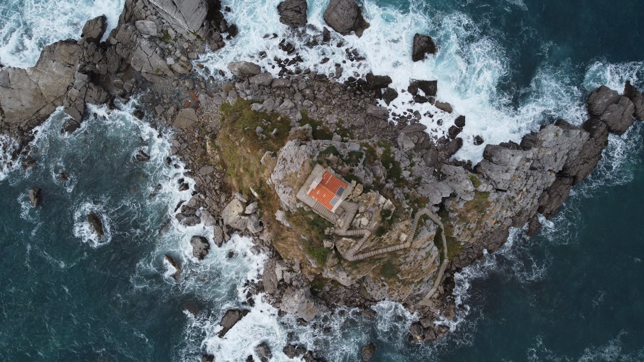 A dramatic aerial shot of Sveta Nedjelja Island's rocky terrain and church in Montenegro.
